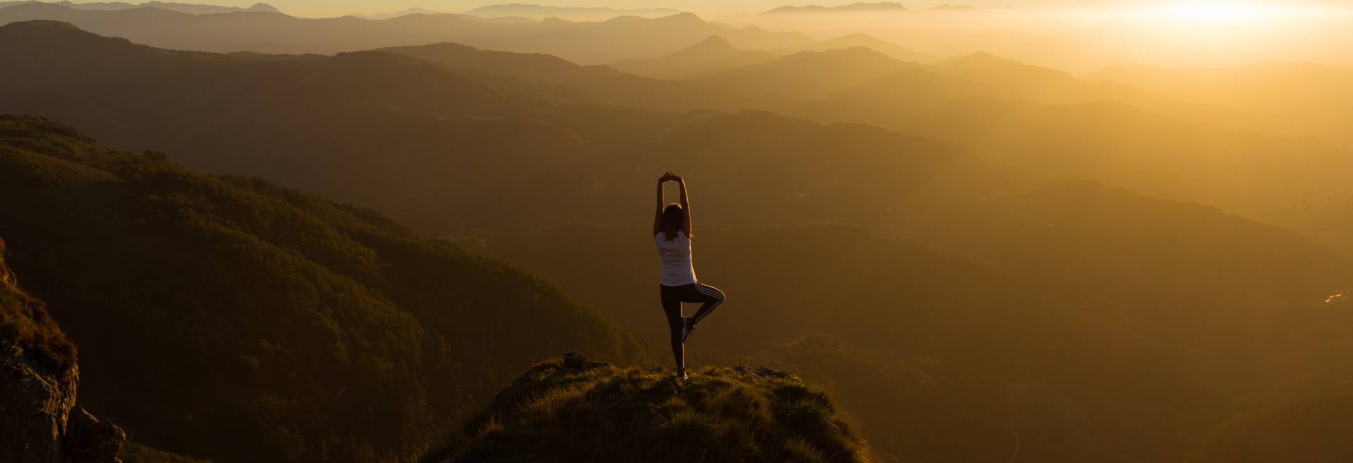 Image of a woman stretching on a mountain. 