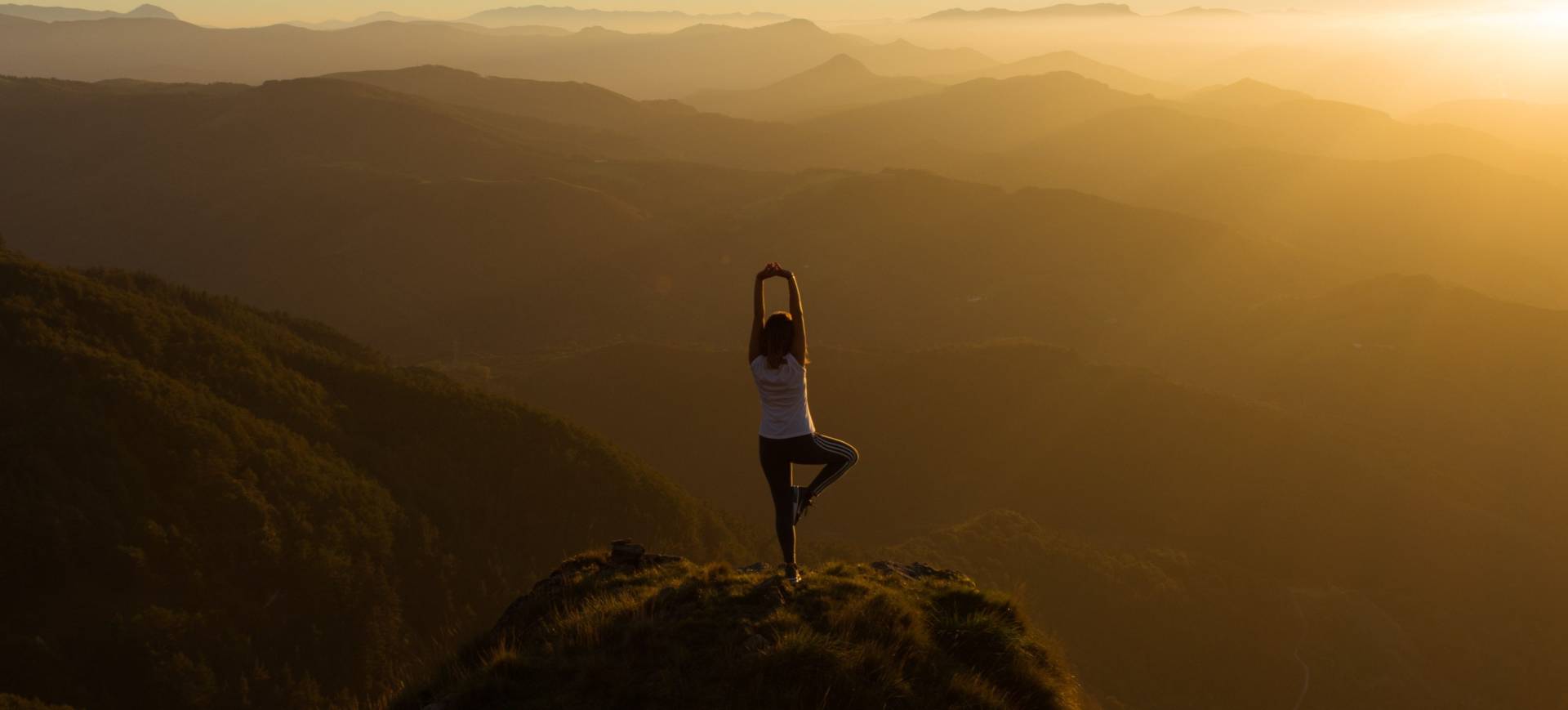 a woman doing yoga on a cliff